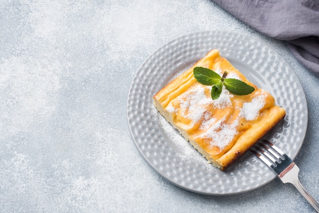 Casseruola di ricotta su un piatto con zucchero a velo e foglie di menta.