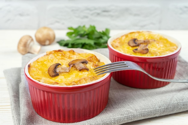 Casseruola francese di Julienne con pollo e funghi in una porzione di ramekin su sfondo bianco