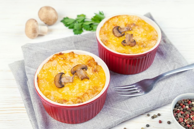 Casseruola francese di Julienne con pollo e funghi in una porzione di ramekin su sfondo bianco