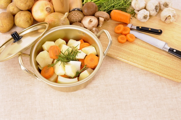 Casseruola o pentola con verdure biologiche e tagliere sulla tovaglia di lino.