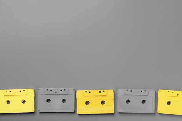 Cassette audio gialle e grigie su sfondo grigio vista dall'alto, copia dello spazio