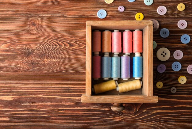 Cassetto in legno con fili per cucire colorati e bottoni sulla vista del tavolo