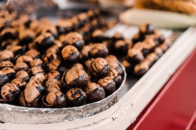 Castagne arrostite in padella. Snack di castagne alla griglia sul mercato di strada