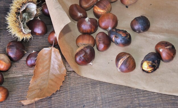 Castagne arrostite su carta su carta su un tavolo di legno