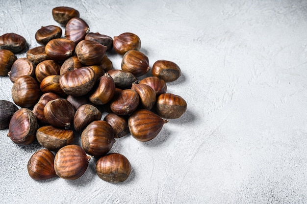 Castagne crude su un tavolo di legno. Sfondo bianco. Vista dall'alto. Copia spazio.