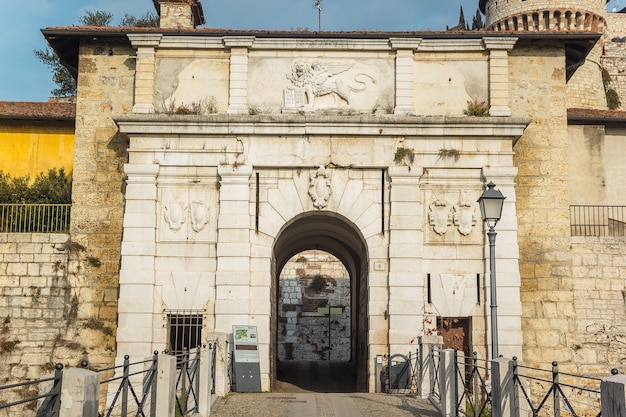 Castello di Brescia. L'ingresso della fortezza medievale con la scultura del leone. Il castello ha torri, una trincea, un ponte fatto di pietre di marmo bianco, mattoni, in una città italiana Brescia, Lombardia