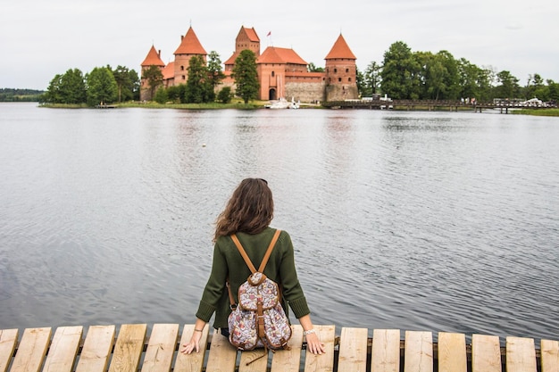 Castello di Trakai in Lituania. Giovane donna (vista posteriore) seduta sul molo e guardando il castello