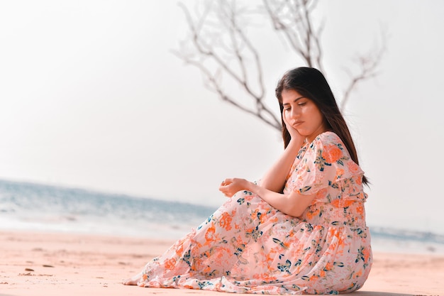 casual gioiosa bella ragazza posa anteriore seduta sulla spiaggia modello pakistani indiano