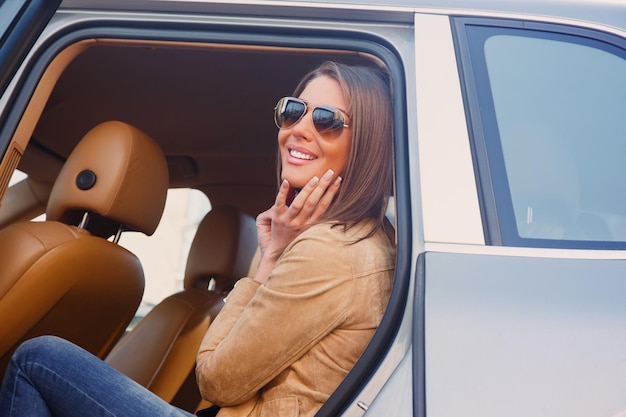 Casual ragazza sorridente in occhiali da sole sul sedile posteriore di un'auto.