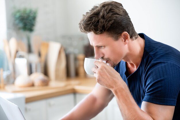 Casual uomo bere caffè al mattino mentre si lavora a casa