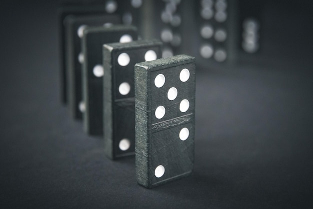 Catena del domino nera su sfondo scuro del tavolo