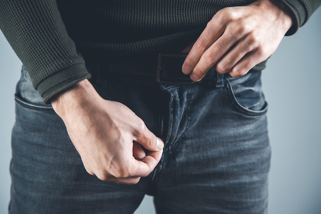 Catena della mano dell'uomo in pantaloni su sfondo grigio