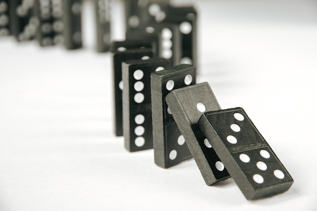 Catena di domino nera su sfondo bianco del tavolo Concetto di effetto domino