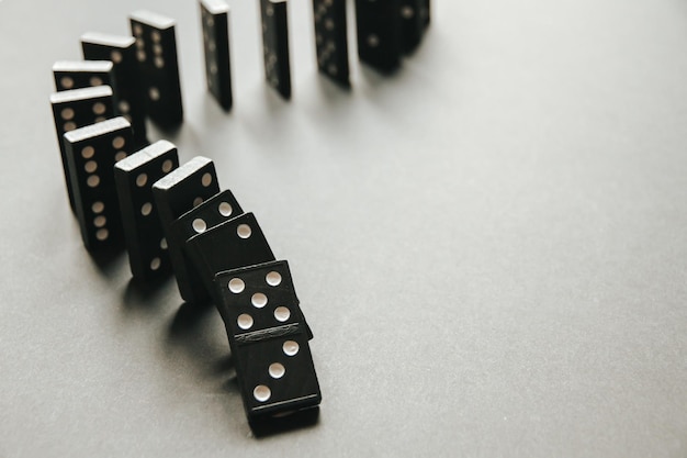 Catena di domino nera su sfondo bianco del tavolo Concetto di effetto domino