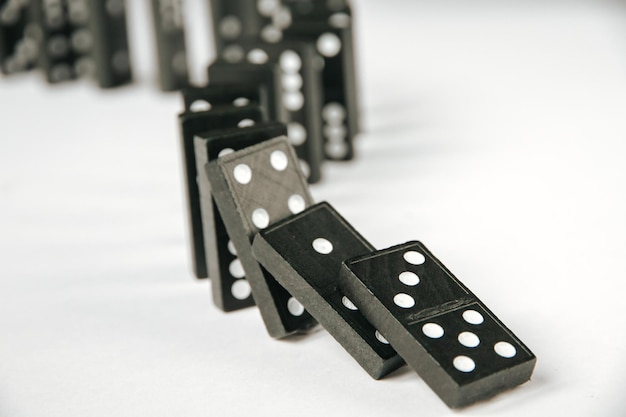 Catena di domino nera su sfondo bianco del tavolo Concetto di effetto domino