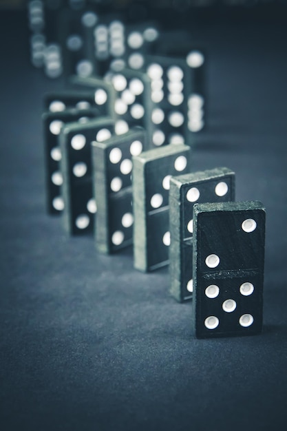 Catena di domino nera su sfondo scuro del tavolo Concetto di effetto domino