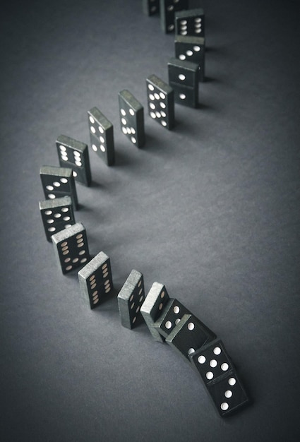 Catena di domino nera su sfondo scuro del tavolo Concetto di effetto domino