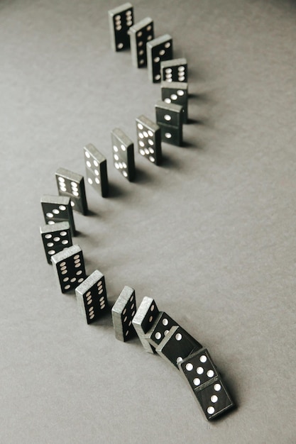 Catena di domino nera su uno sfondo di tabella Concetto di effetto domino