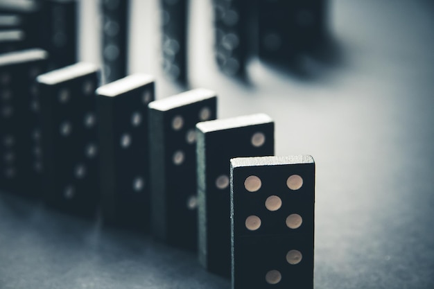 Catena di domino nera su uno sfondo di tabella Concetto di effetto domino