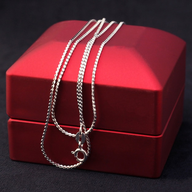 Catena di gioielli in argento o oro bianco su scatola regalo rossa.