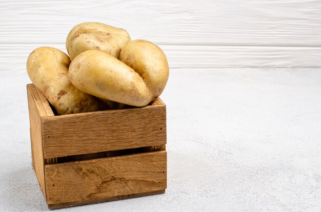 Cattivissime patate di diverse forme in una scatola di legno, copia spazio.