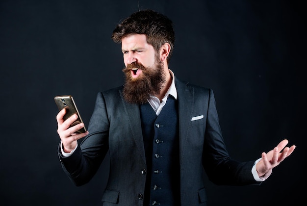 Cattivo feedback da parte del cliente uomo barbuto arrabbiato con smartphone uomo d'affari brutale hipster caucasico in tuta online e agile Hipster maturo con barba parla al telefono uomo stressato che grida