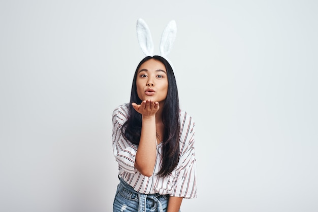 Cattura da vicino una giovane donna asiatica carina con orecchie da coniglio e abiti casual che soffiano