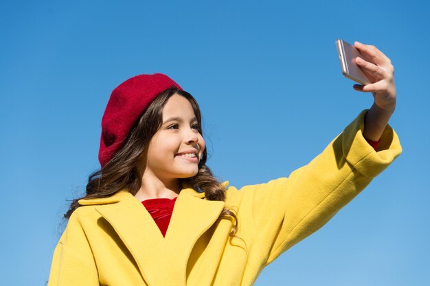 Catturare la bellezza. Smartphone o telefono cellulare della stretta della bambina. Il bambino comunica con il telefono cellulare degli amici. Scattare foto di selfie. Comunicazione di generazione moderna. Concetto di comunicazione mobile.