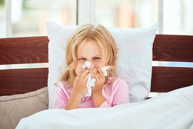 Catturare un ritratto freddo di una bambina malata con naso che cola che soffre di raffreddore o