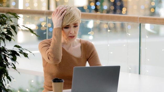 Caucasica di mezza età, donna d'affari matura con laptop, problemi di lavoro con il computer di pagamento.