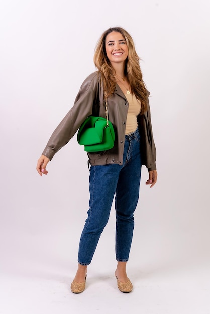 Caucasica donna bionda sorridente con un sacchetto verde su uno studio di moda sfondo bianco