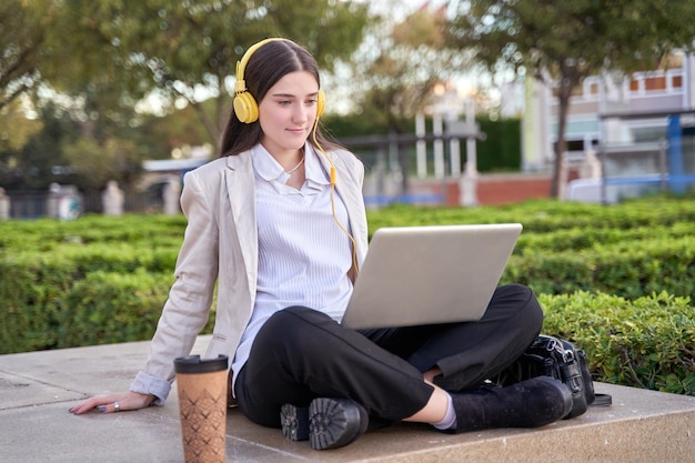 Caucasica studente di college femminile utilizzando il suo computer portatile nel campus universitario con le cuffie
