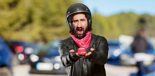 Cavaliere della motocicletta che tiene un modello di auto rossa