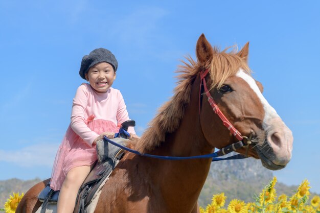 Cavallo da equitazione ragazza carina felice in campo di girasole