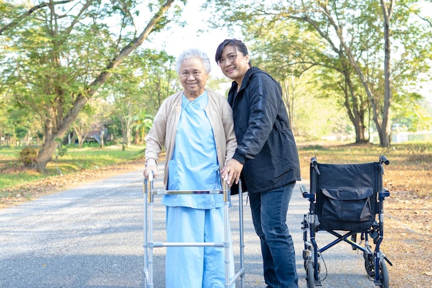 Cavernatore aiuto e cura Asiatica anziana o anziana donna anziana con una forte salute mentre si cammina al parco in felice vacanza fresca
