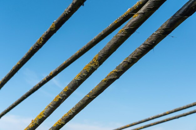 Cavi e corde di un ponte sospeso in primo piano Fissaggio del vecchio ponte sul fiume Cavi di ferro arrugginiti contro un cielo blu