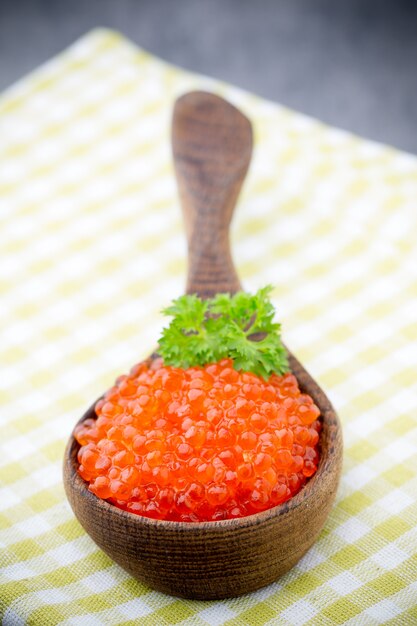 Caviale di salmone con cucchiaio sulla superficie grigia.