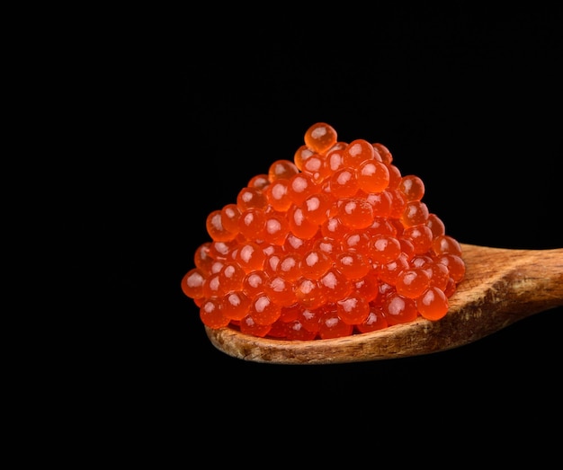 Caviale di salmone rosso fresco e granulato in un cucchiaio di legno cibo delizioso e sano da vicino