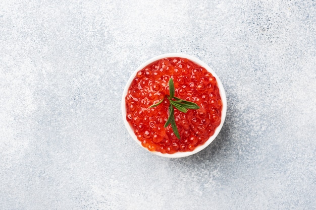 Caviale di salmone rosso in un piatto su sfondo grigio cemento. Prelibatezza di snack. Copia spazio.