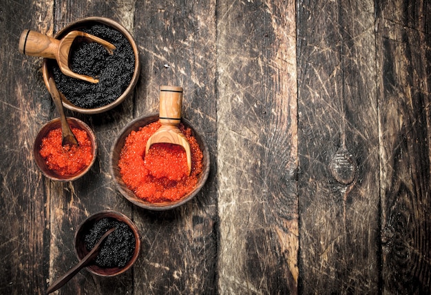 Caviale nero e rosso in vecchie ciotole di legno. Sullo sfondo di legno.