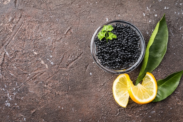 Caviale nero in una ciotola di vetro con il limone si chiuda