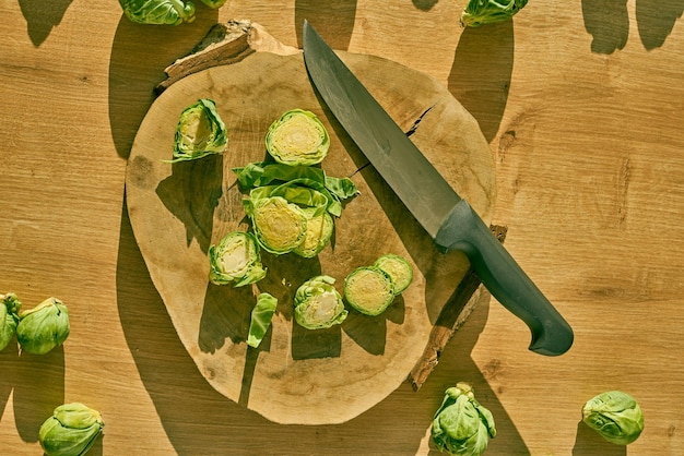 Cavoletti di Bruxelles affettati e un coltello da chef su un bancone da cucina in legno.
