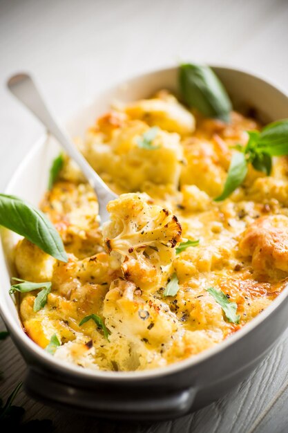 Cavolfiore al forno con verdure e formaggio e uova strapazzate in un piatto di ceramica