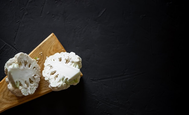 Cavolfiore tagliato a metà su sfondo scuro Cucinare una bistecca di cavolfiore Concetto di dieta alimentare vegetariana