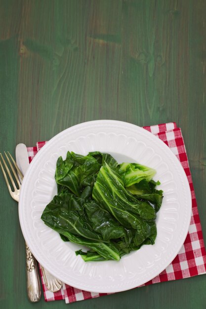 Cavolo bollito sul piatto bianco sulla tavola di legno verde