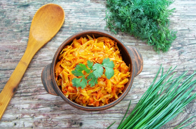 Cavolo brasato, stufato con salsa di pomodoro, servito in una ciotola sul tavolo di legno con cipolla verde e aneto.