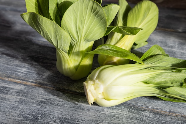 Cavolo cinese fresco bok choy o pac choi su un fondo di legno grigio.