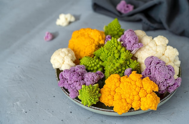 Cavolo di cavolfiore diverso sul piatto e fondo di cemento grigio con tovagliolo