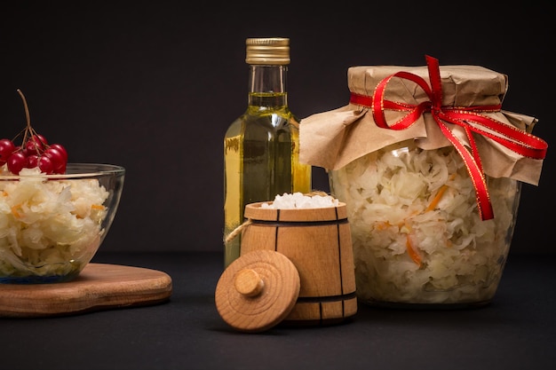 Cavolo fermentato fatto in casa in una ciotola di vetro e un barattolo di legno con sale