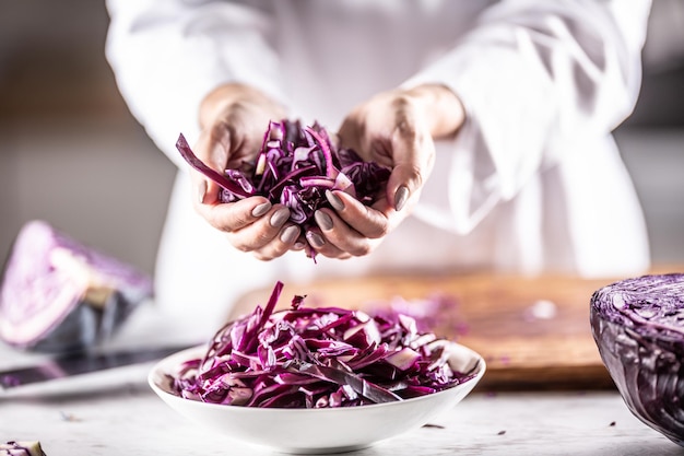 Cavolo rosso crudo affettato sottilmente nelle mani e all'interno della ciotola di uno chef professionista.